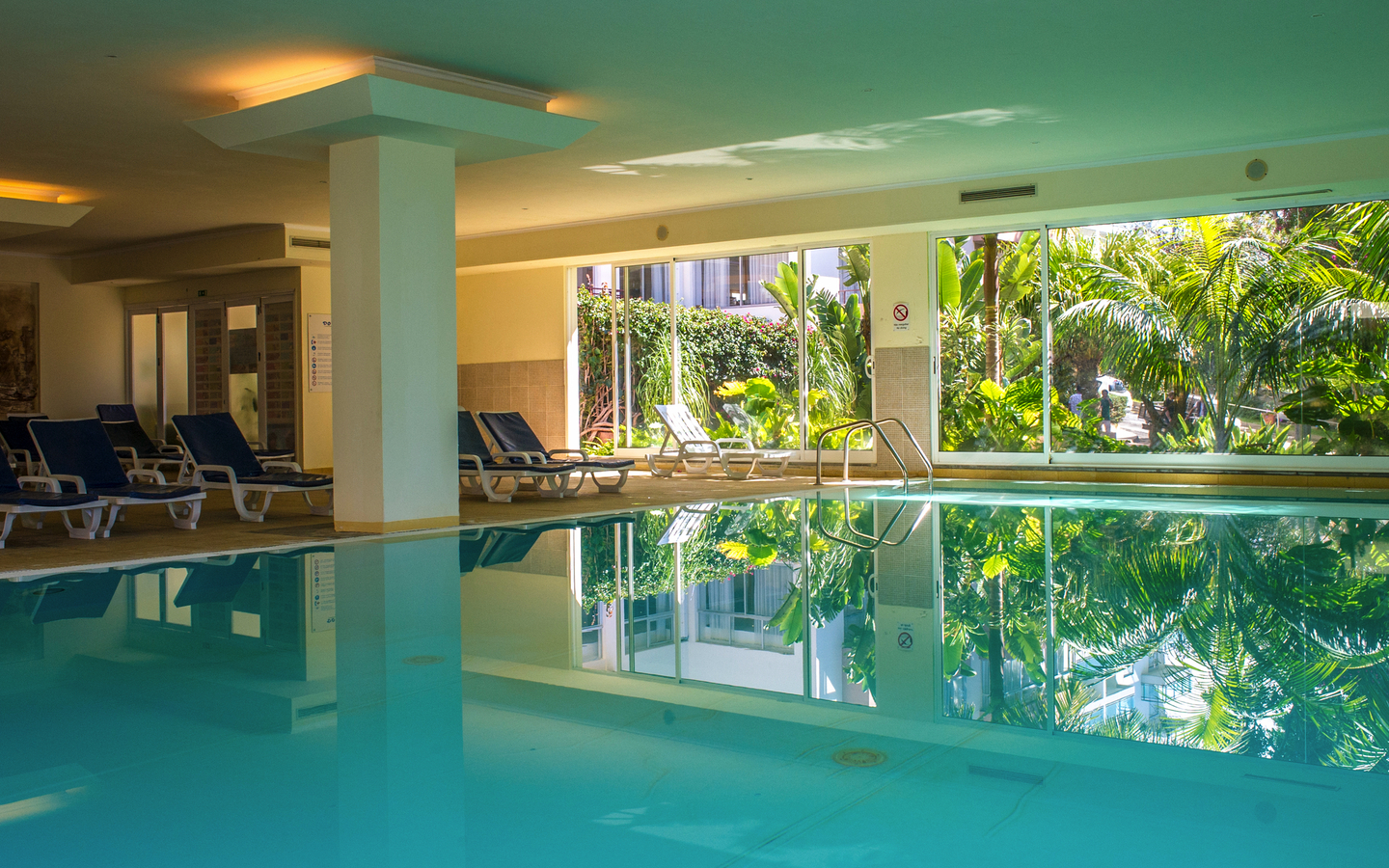 Innenpool mit Liegestühlen und großen Fenstern im Hotel Dorisol Estrelicia