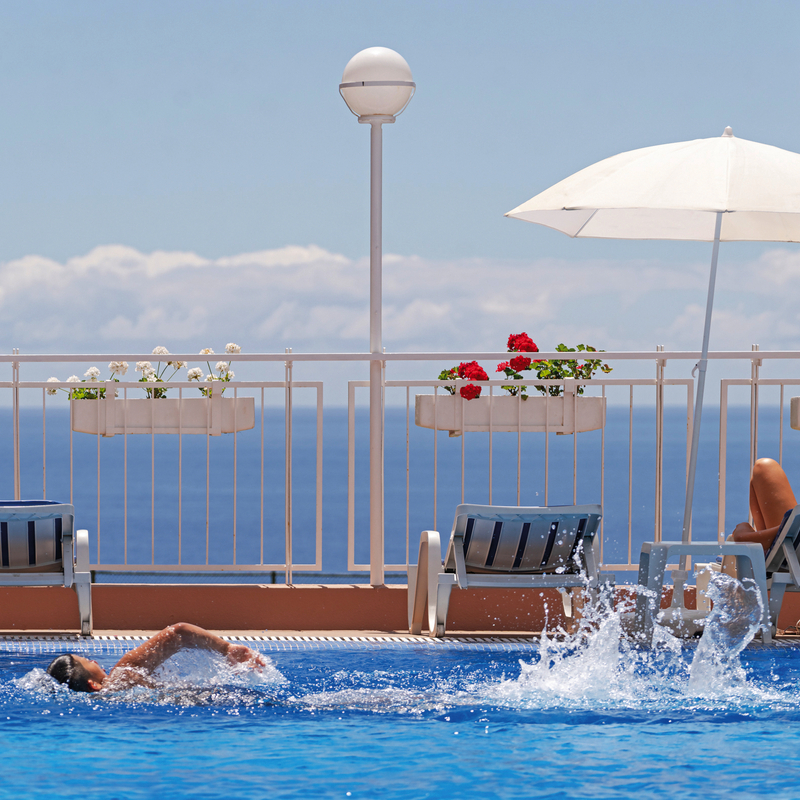 Pool mit Schwimmer und Liegen im Hotel Dorisol Estrelicia auf Madeira.