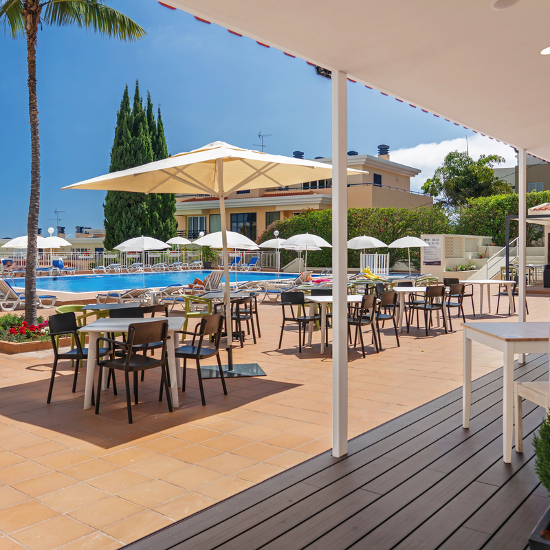 Poolbereich mit Tischen und Sonnenschirmen am Hotel Dorisol Estrelicia in Funchal, Madeira.