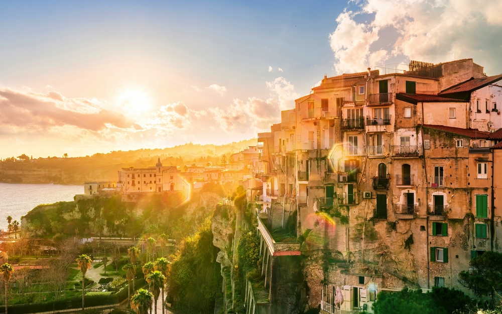 Sonnenuntergang über einer Küstenstadt in Kalabrien mit historischen Gebäuden.