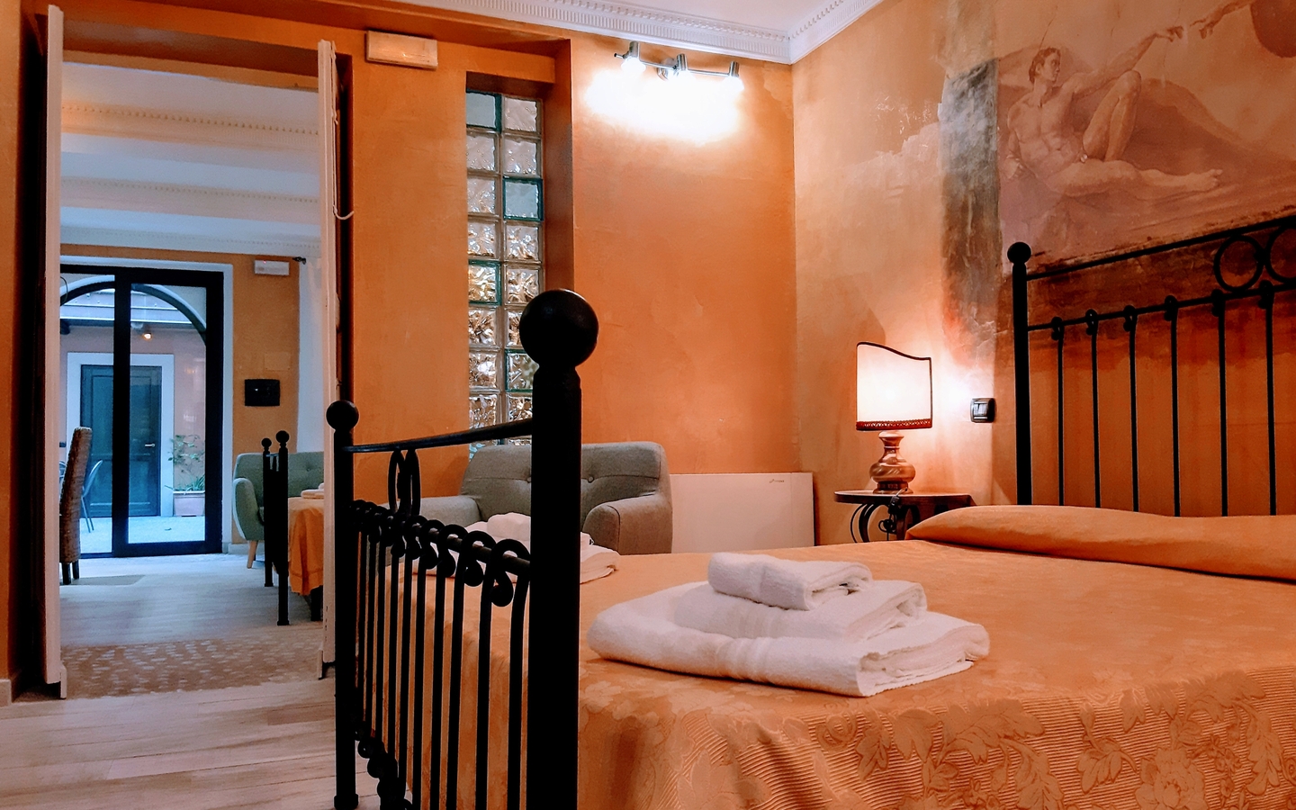 Hotelzimmer mit Doppelbett, Nachttischlampe und offenen Türen zum Flur und Hof.