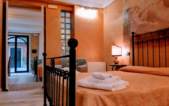 Hotelzimmer mit Doppelbett, Nachttischlampe und offenen Türen zum Flur und Hof.