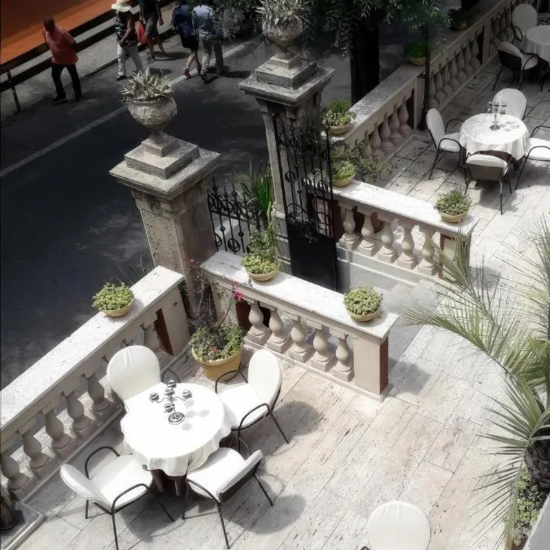 Terrasse des Hotel Villa Antica Tropea mit weißen Tischen und Stühlen.