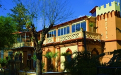 Außenansicht des Hotels Villa Antica Tropea mit Bäumen und Palmen.