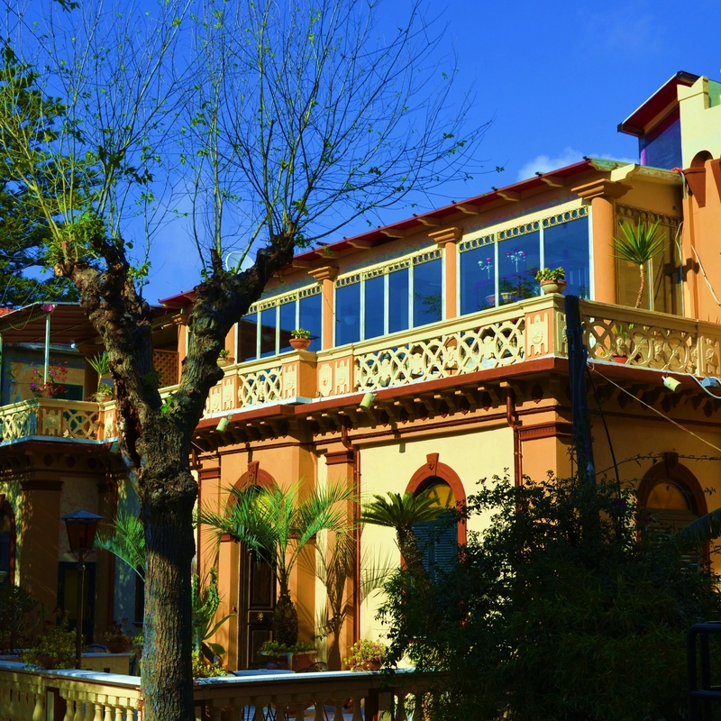 Außenansicht des Hotels Villa Antica Tropea mit Bäumen und Palmen.
