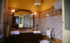 Hotelbad mit Waschbecken, Spiegel, Handtüchern und Fliesenwänden in warmen Farben.