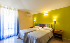 Zwei Einzelbetten im Hotelzimmer mit moderner Einrichtung in kaltem Licht.