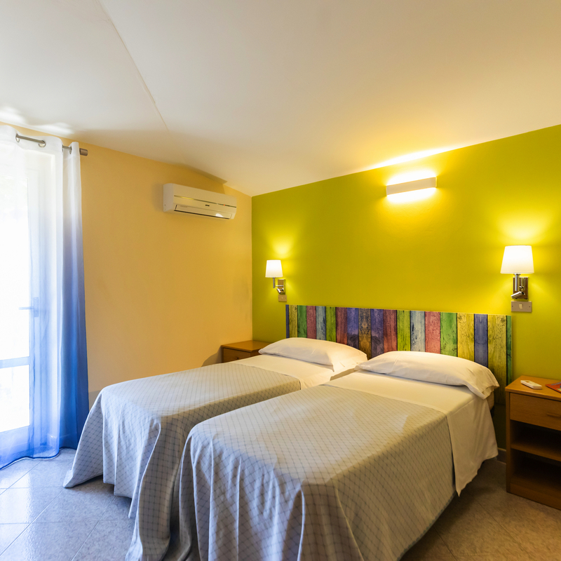 Zwei Einzelbetten im Hotelzimmer mit moderner Einrichtung in kaltem Licht.