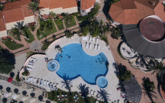 Luftaufnahme eines Hotelpools mit umliegenden Gebäuden und Palmen