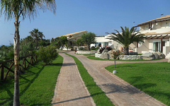 Gepflegter Gartenweg zum Hotelgebäude, umgeben von Palmen und Sträuchern.