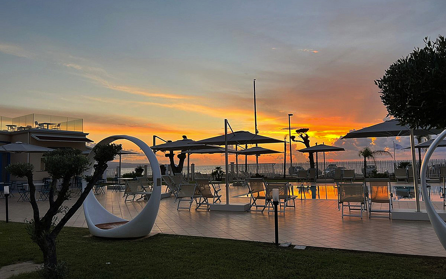 Poolbereich des Resorts Galia Luxury bei Sonnenuntergang, umgeben von modernen Liegen und Pflanzen.