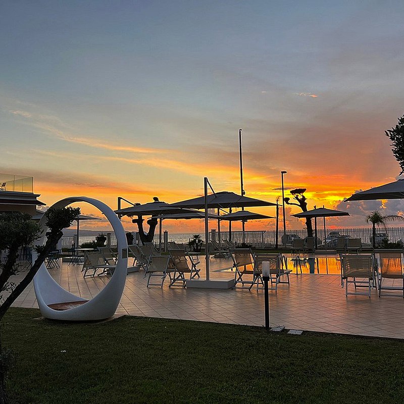 Poolbereich des Resorts Galia Luxury bei Sonnenuntergang, umgeben von modernen Liegen und Pflanzen.