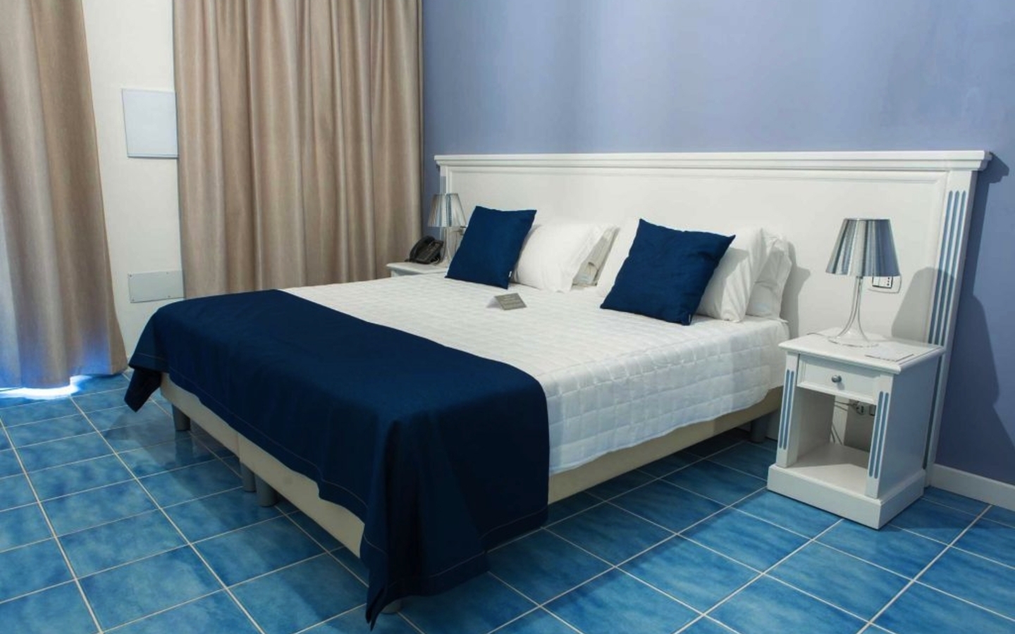 Hotelzimmer mit Doppelbett, blauer Bettdecke und Nachttischen im Galia Luxury Resort