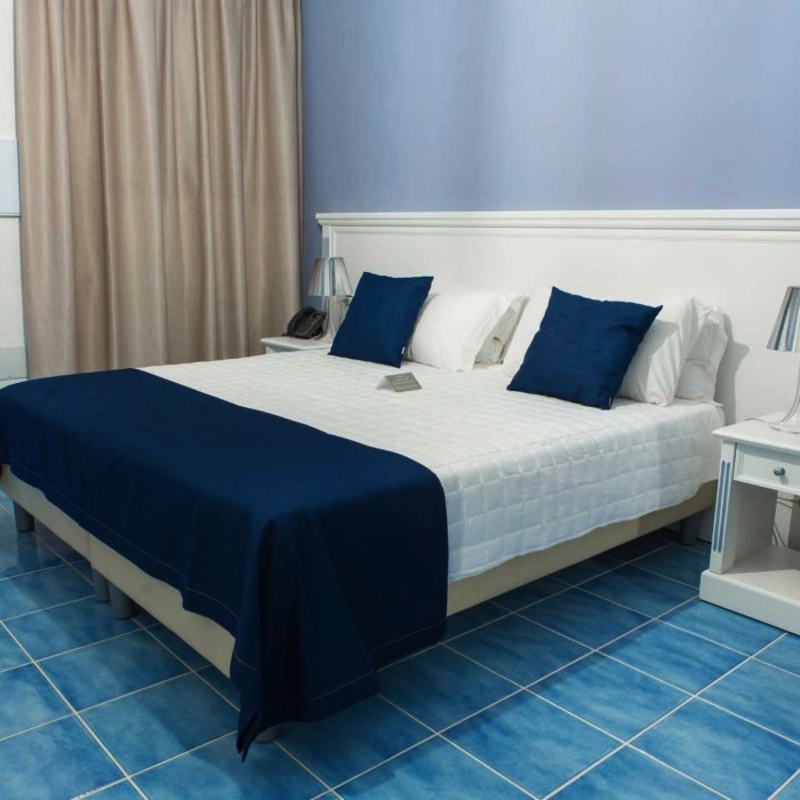 Hotelzimmer mit Doppelbett, blauer Bettdecke und Nachttischen im Galia Luxury Resort
