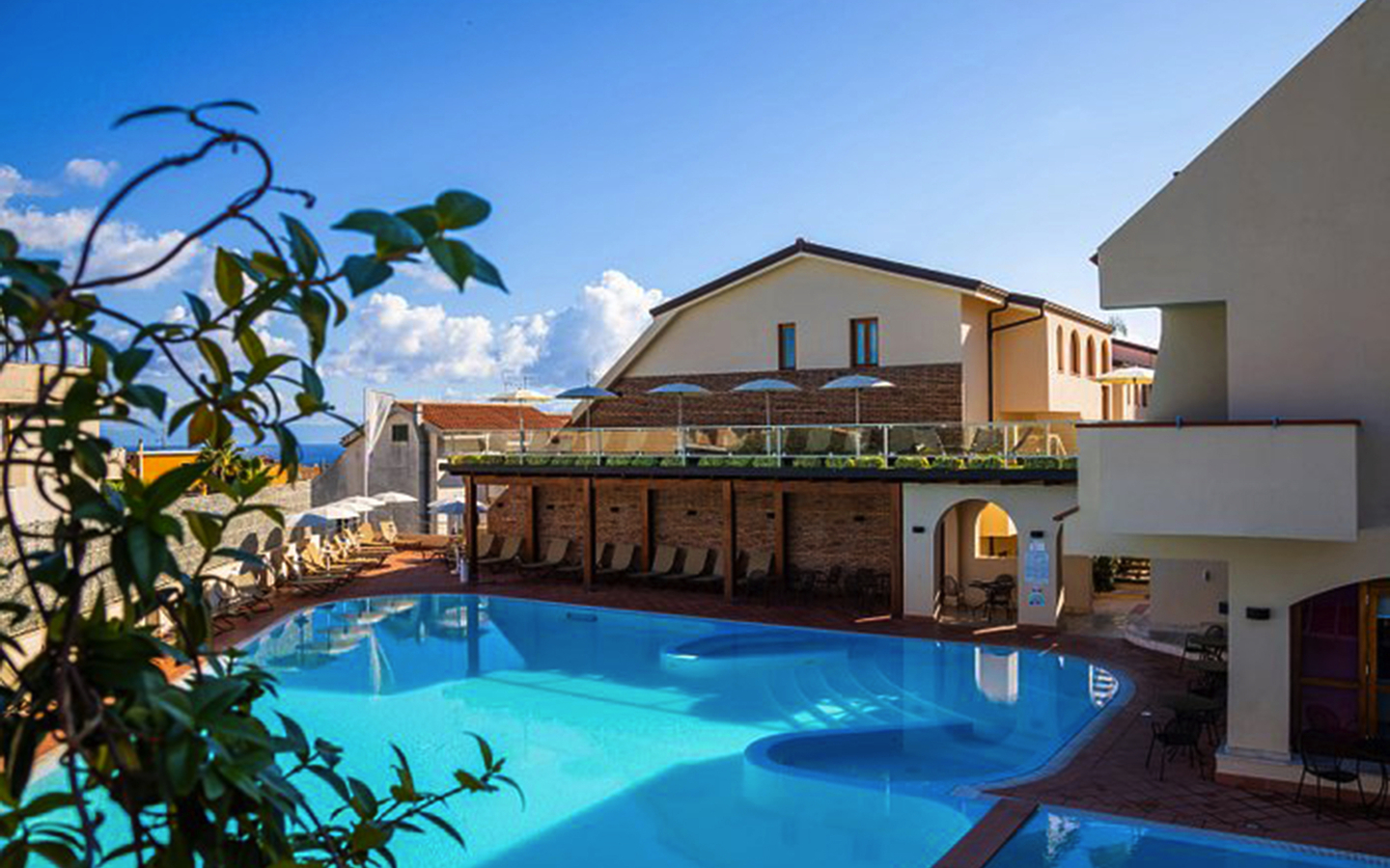 Hotelkomplex mit Pool und Sonnenschirmen in tropischer Umgebung.