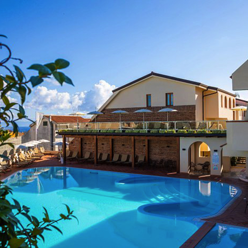 Hotelkomplex mit Pool und Sonnenschirmen in tropischer Umgebung.