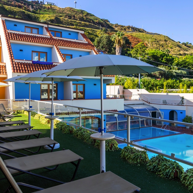 Außenbereich des Hotel Tropis mit Pool und Liegestühlen in Tropea, Kalabrien.