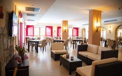 Helles Hotel-Restaurant mit modernen Möbeln und rotem Fensterakzent.