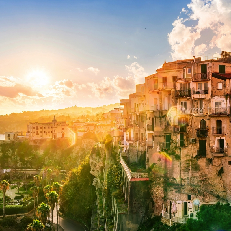 Sonnenuntergang über einer Küstenstadt in Kalabrien mit historischen Gebäuden.