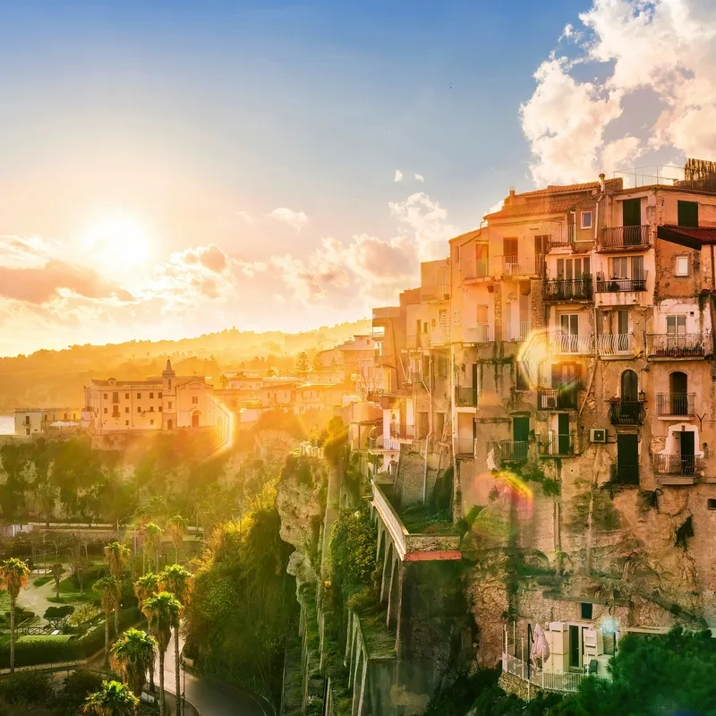 Sonnenuntergang über einer Küstenstadt in Kalabrien mit historischen Gebäuden.