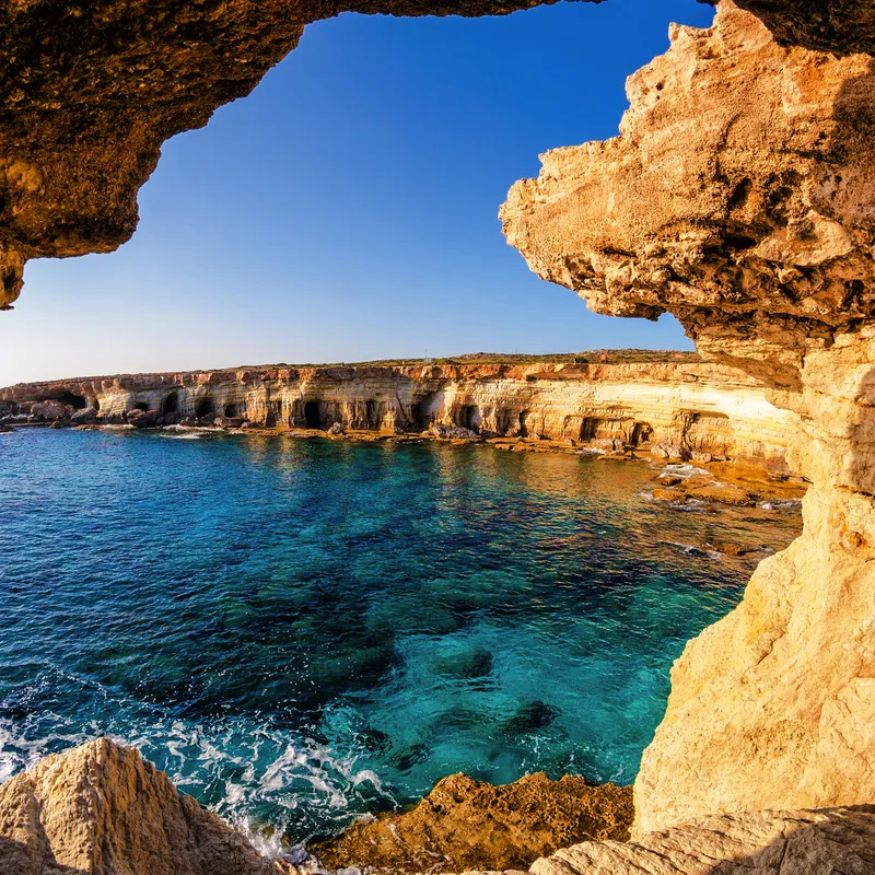 Küstenlandschaft bei Agia Napa auf Zypern mit azurblauem Meer und Felsformationen im Vordergrund.