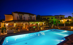 Beleuchteter Hotelpool bei Nacht vor einem Gebäude in Griechenland.