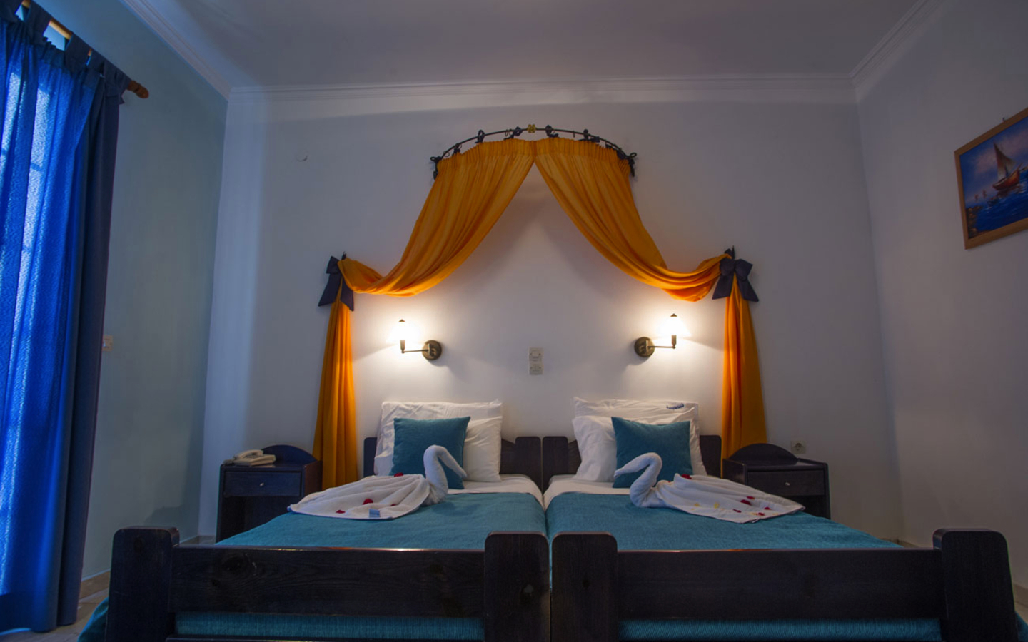 Ein Doppelzimmer mit Betten, Baldachin, blauer Bettwäsche und Wanddekoration.