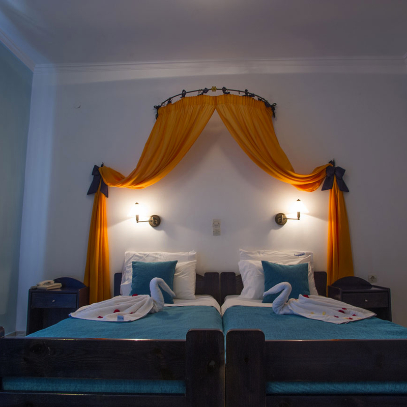 Ein Doppelzimmer mit Betten, Baldachin, blauer Bettwäsche und Wanddekoration.