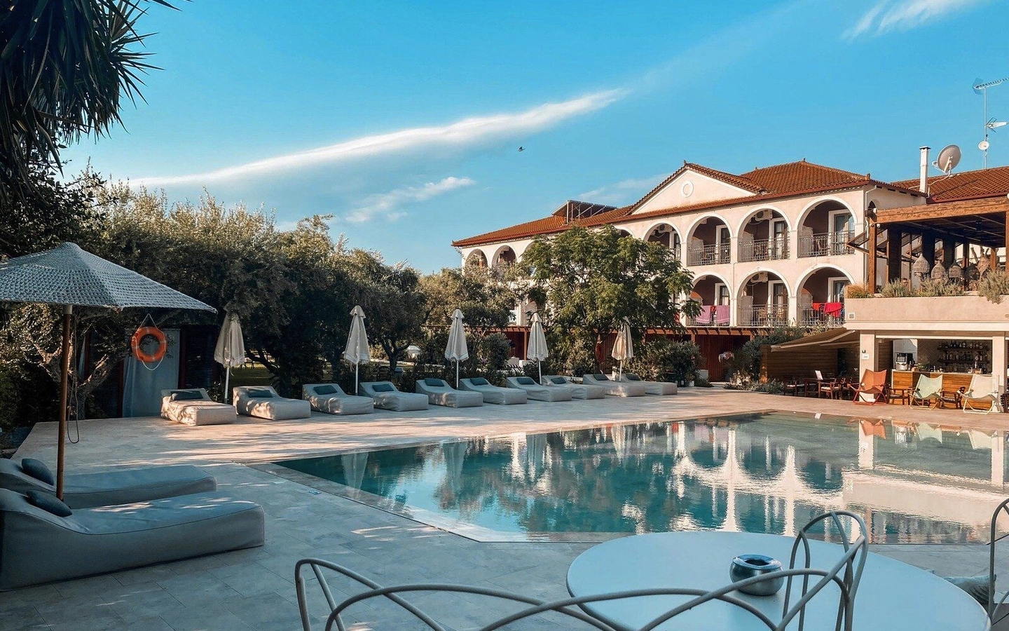 Außenansicht des Castelli Hotels mit Pool und Liegestühlen.