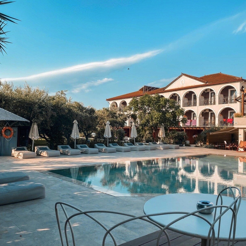 Außenansicht des Castelli Hotels mit Pool und Liegestühlen.