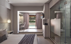 Modernes Hotelzimmer mit Bett, Glaswand und Blick auf Pool.