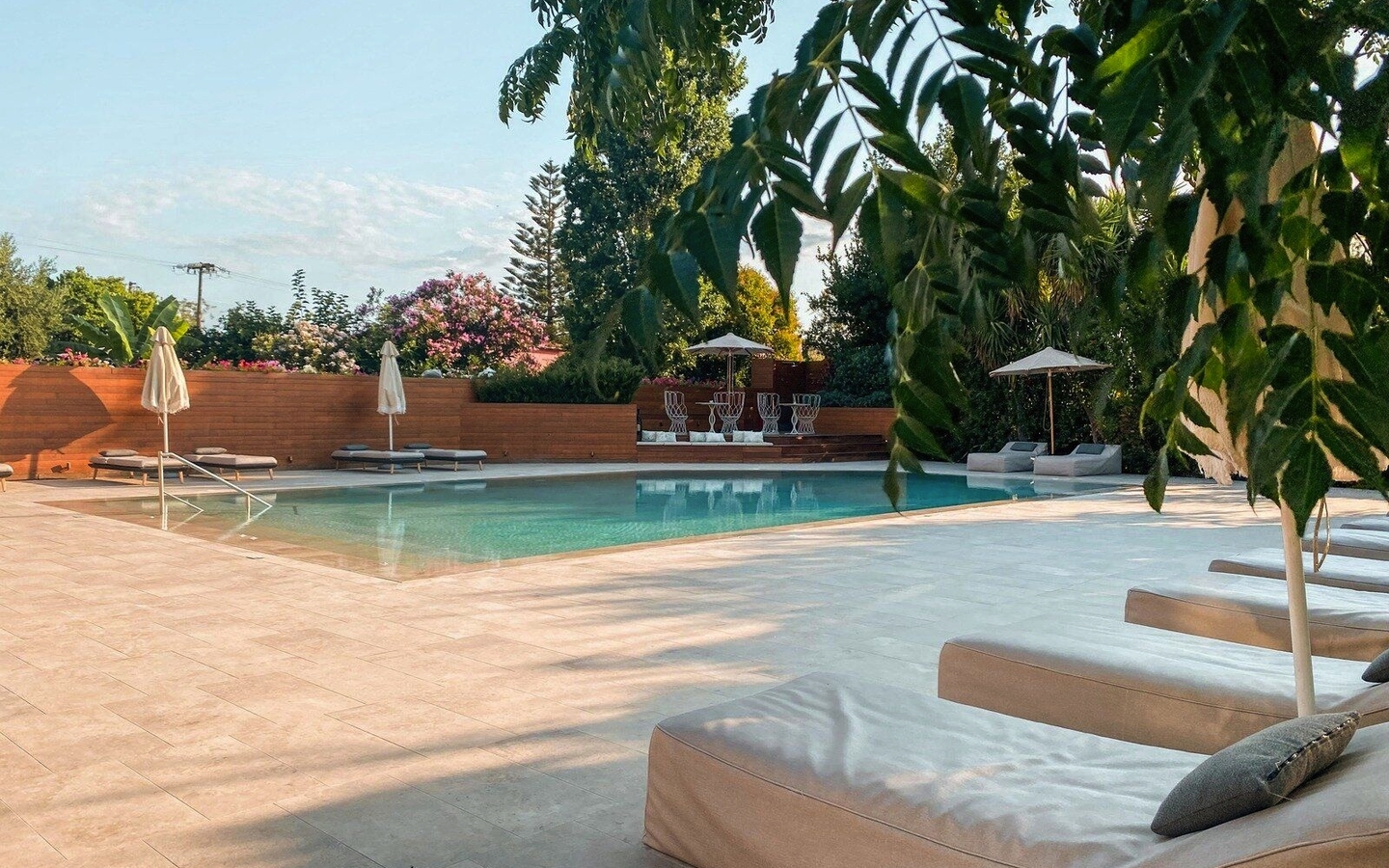 Poolbereich mit Liegen und Sonnenschirmen, umgeben von Bäumen im Castelli Hotel, Zakynthos.
