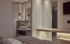 Modernes Hotelzimmer mit Doppelbett, Badbereich und Spiegeln.