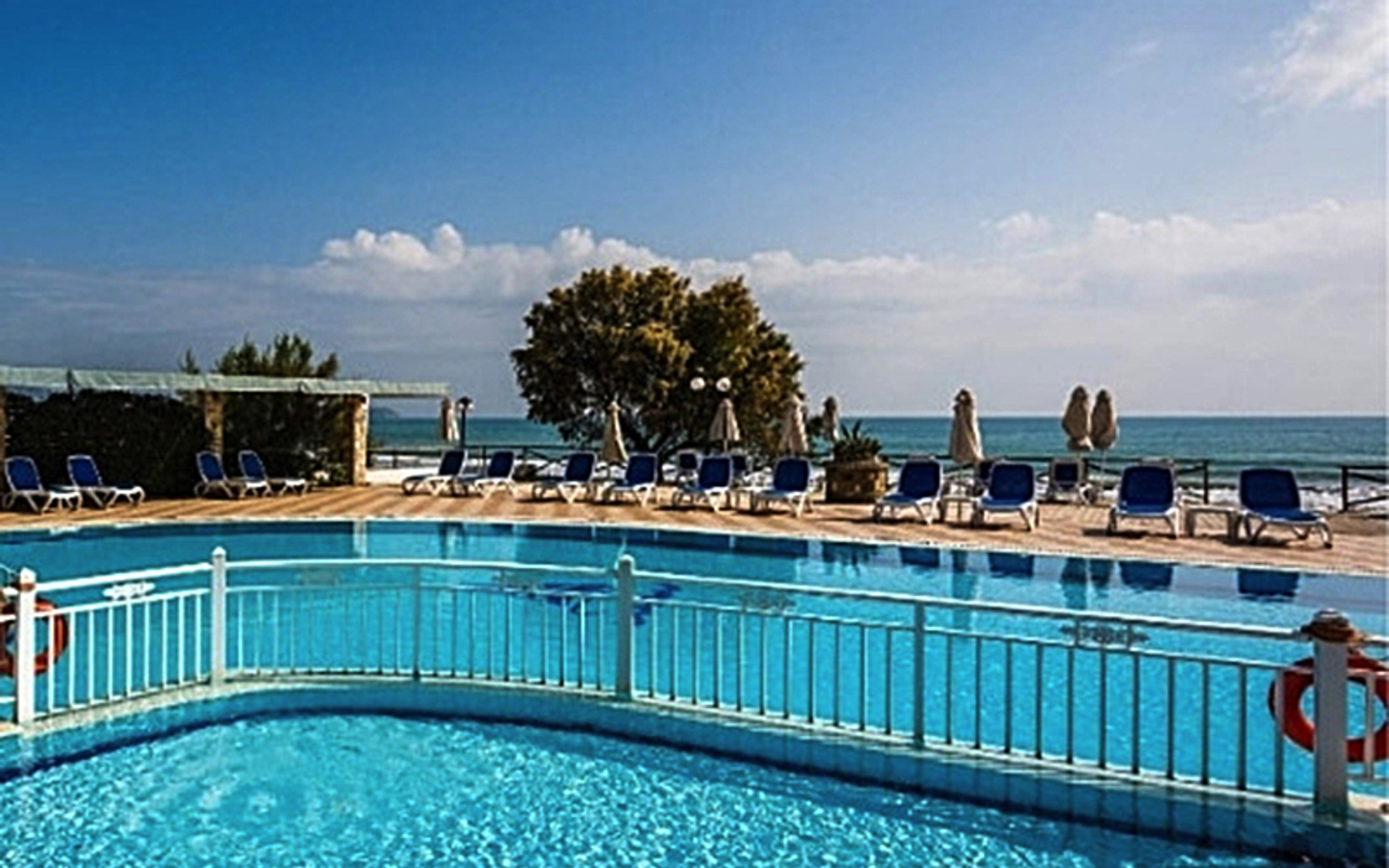 Außenpool mit Liegestühlen und Blick auf das Meer im Hotel Mediterranean Beach Resort