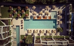 Luftaufnahme eines Hotelpools mit umliegenden Liegen und Sonnenschirmen.