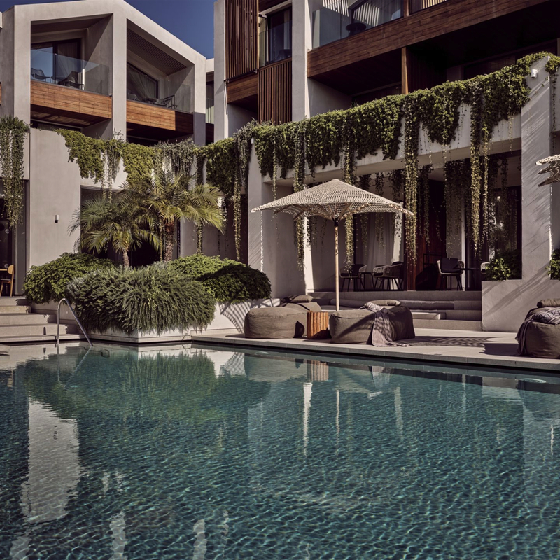Hotelpool mit Liegestühlen, Sonnenschirmen und moderner Architektur im Hintergrund