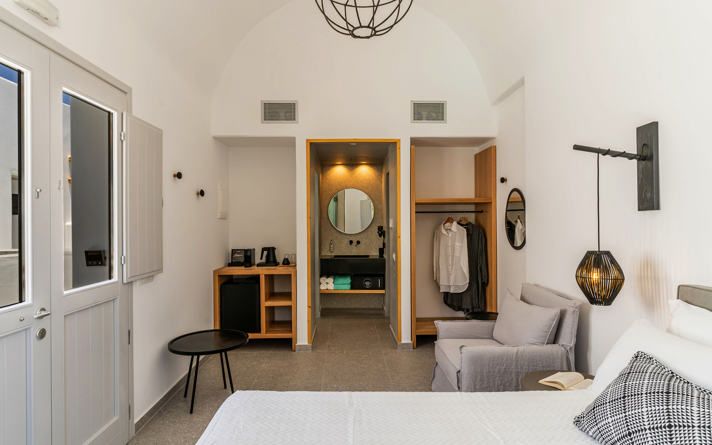 Helles Hotelzimmer mit Bett, Sofa, Schreibtisch und offenen Kleiderschrank.
