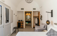 Helles Hotelzimmer mit Bett, Sofa, Schreibtisch und offenen Kleiderschrank.