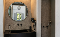 Modernes Hotelbad mit rundem Spiegel, Waschtisch und Regendusche.