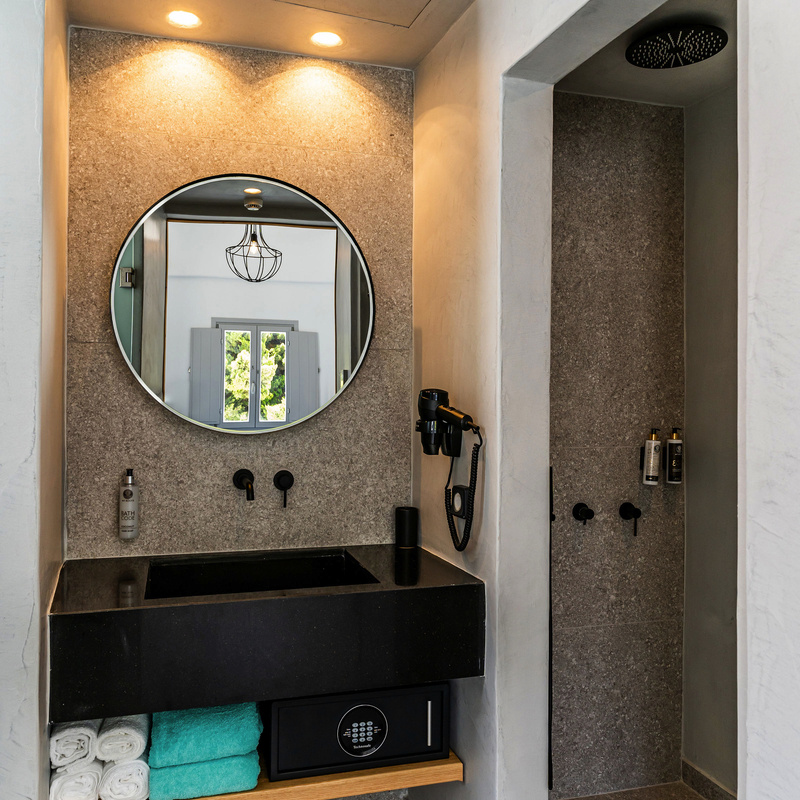 Modernes Hotelbad mit rundem Spiegel, Waschtisch und Regendusche.