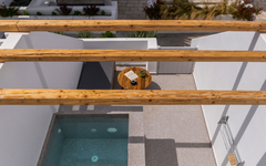 Blick von oben auf einen kleinen Pool und eine Terrasse mit Sonnenliegen in Santorin.