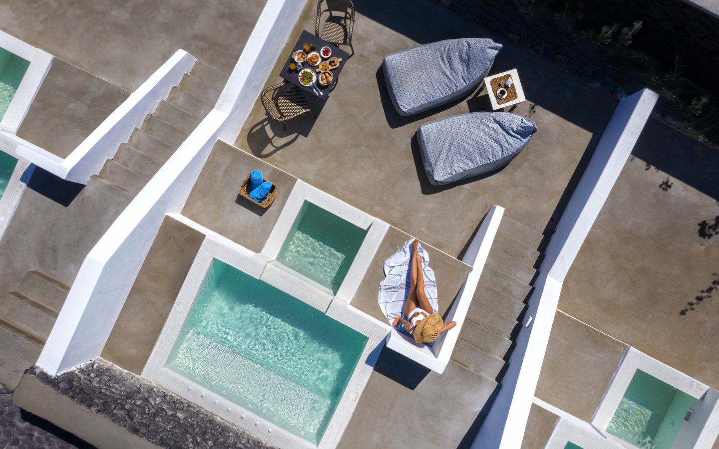 Hotelterrasse mit Pool und Liegen in sonniger Umgebung.