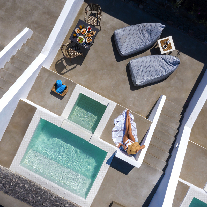 Hotelterrasse mit Pool und Liegen in sonniger Umgebung.