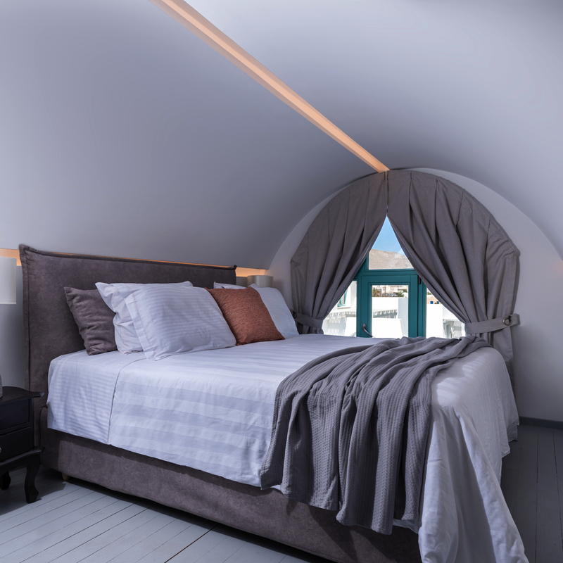 Luxuriöses Hotelzimmer mit gewölbter Decke und gemütlichem Bett in Santorin.