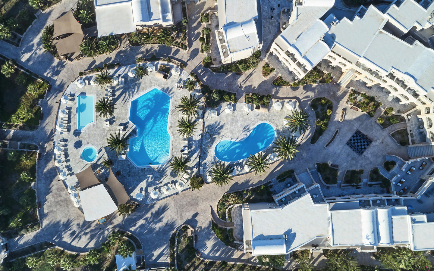 Luftaufnahme eines Hotelresorts mit Pools und Palmen, Santo Miramare, Santorin.