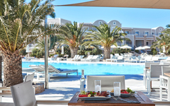 Blick auf den Pool des Hotel Santo Miramare in Santorin mit Tisch im Vordergrund.