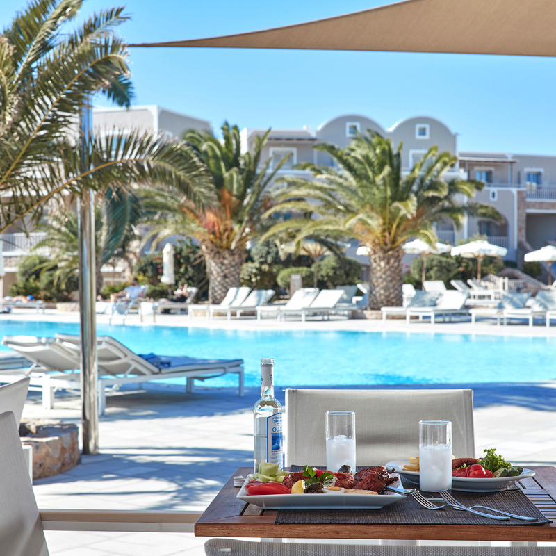 Blick auf den Pool des Hotel Santo Miramare in Santorin mit Tisch im Vordergrund.