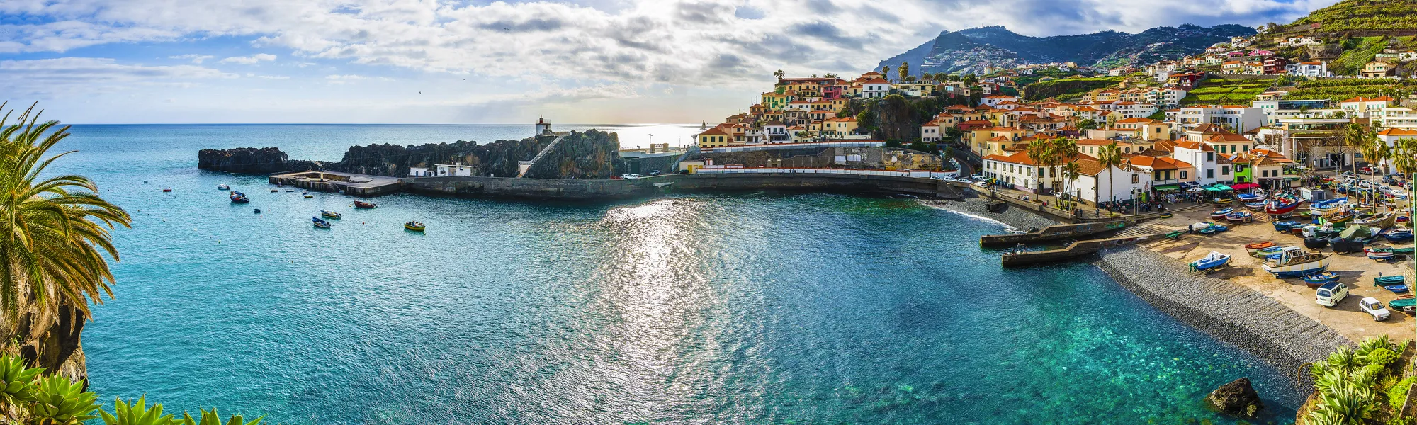 Küstenstadt mit bunten Gebäuden und klarem, blauem Meer unter sonnigem Himmel.
