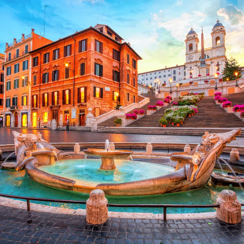 Spanische Treppe in Rom bei Sonnenuntergang mit Barcaccia-Brunnen im Vordergrund.