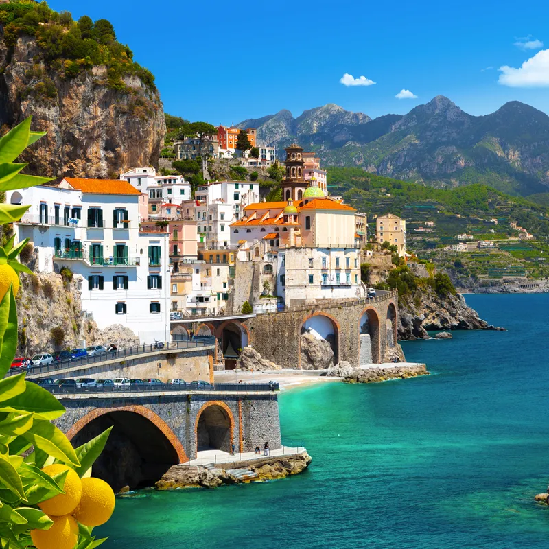 Küstenstadt mit bunten Häusern und Brücke am Meer.